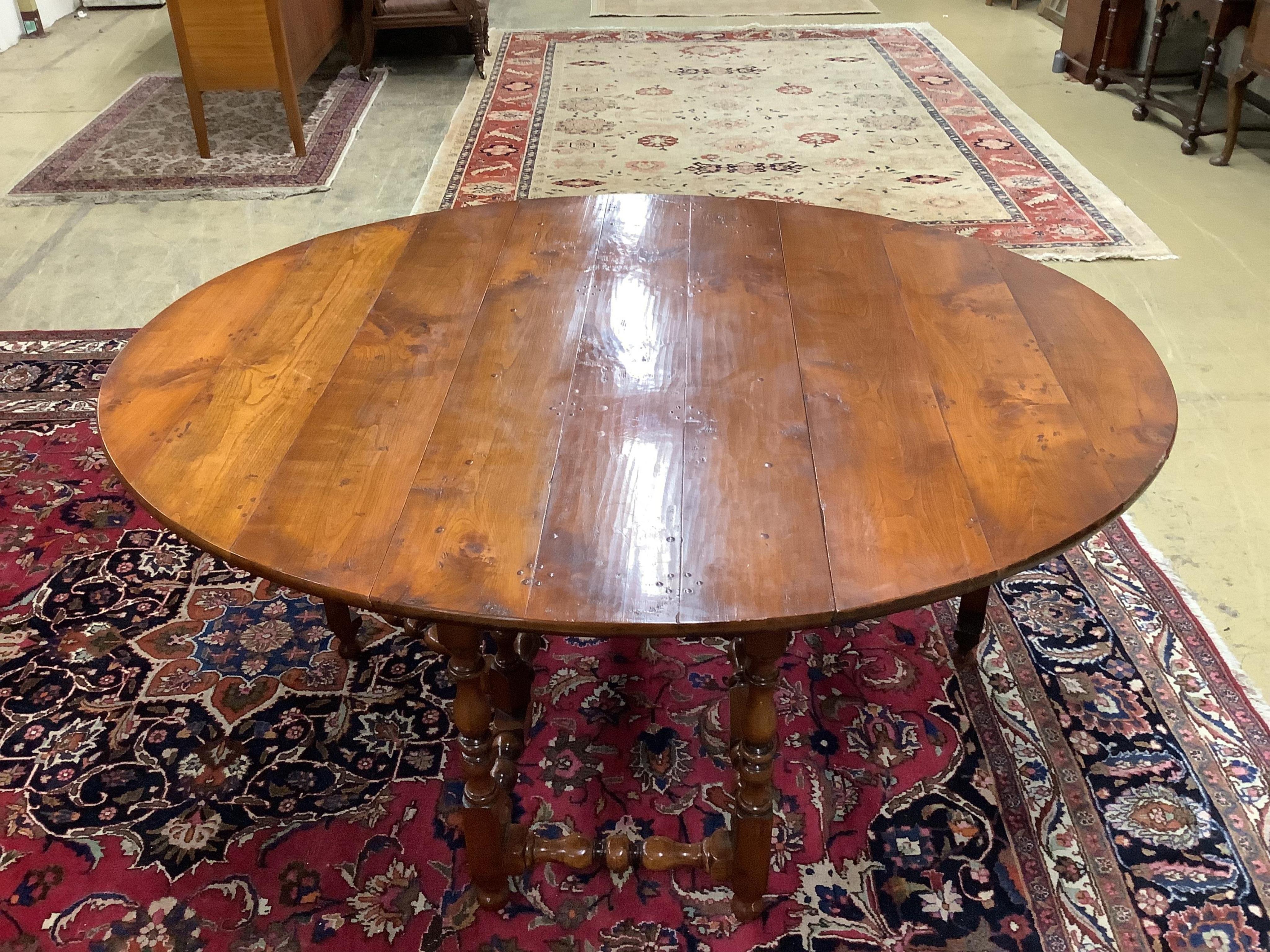 A reproduction 18th century style elm gateleg dining table on turned baluster under frame, width 169cm extended, depth 142cm, height 75cm. Condition - good with a rich colour.